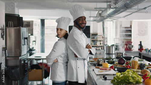 Portrait of chefs doing teamwork to cook food recipe in restaurant kitchen, sitting with arms crossed. Diverse team of cooks preparing to make culinary dish and gourmet meal with fresh ingredients.