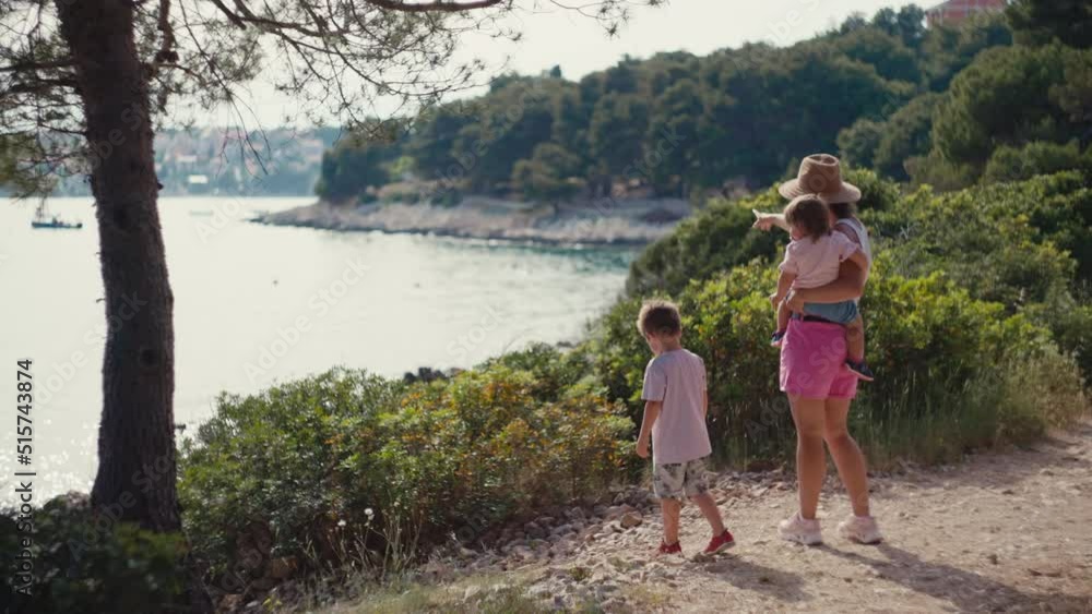 Slow motion video of a family walking happy in the summer by the sea. Mom and children look at the sea in a beautiful landscape on vacation. Slow motion video of a family walking happy in the summer by the sea. Mom and children look at the sea in a beautiful landscape on vacation.