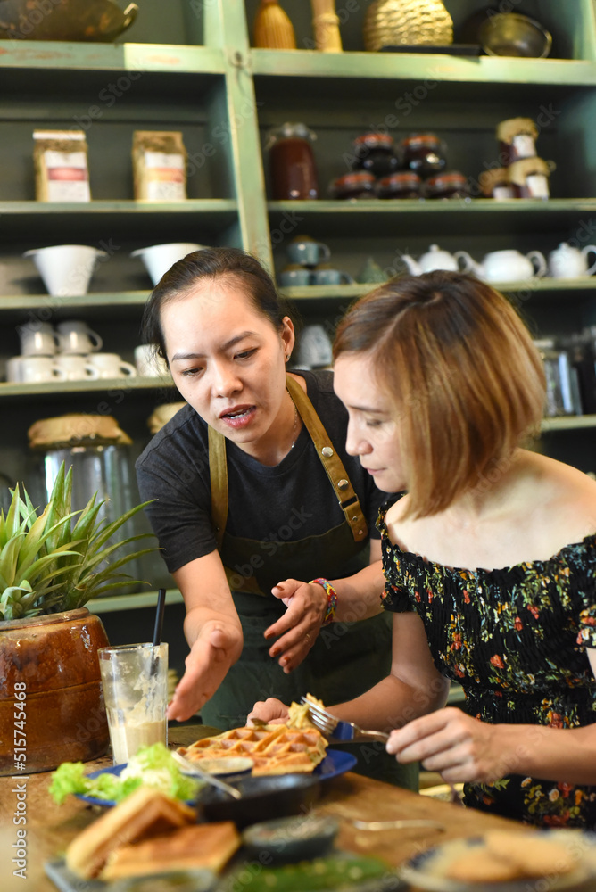 Vietnamese waitress served waffles to a caucasian woman