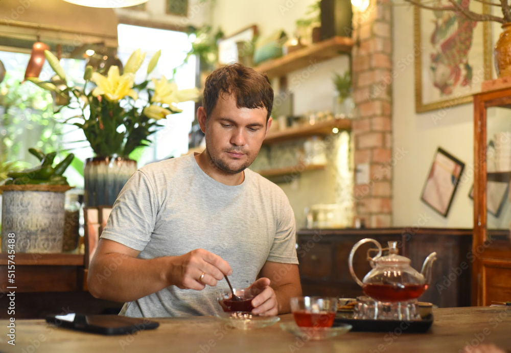 Young man eating homemade jam and tea in cafe Young man eating homemade jam and tea in cafe