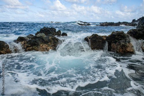 Blue sea and rocks storming. Wave spray over rocks. Rocky sea coast.