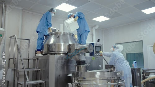 Man pours the liquid substance to automated machine for mixing and making drugs. pharma workers in protective masks and uniform work with medical equipment at medicine manufacturing plant. photo