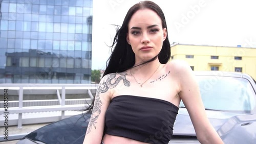 Beautiful brunette girl posing in a black car in the city on a sunny day