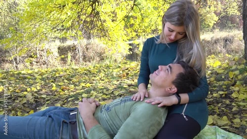 Sweet couple enjoy the autumn landscape sitting under a tree at sunset.