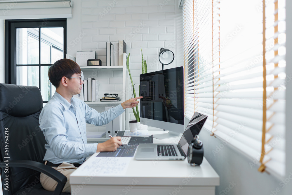 Software development concept, Male programmer checking data codes on document and computer screen Software development concept, Male programmer checking data codes on document and computer screen