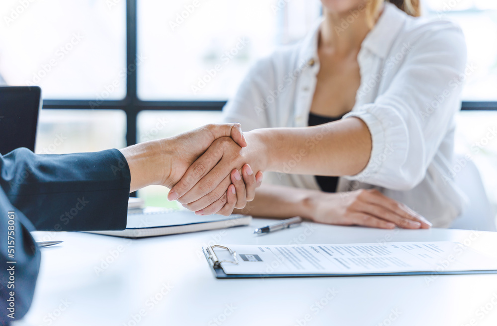 Two Asian beautiful business woman smiling happy and confident shaking hands for agreement at the office. Two Asian beautiful business woman smiling happy and confident shaking hands for agreement at the office.