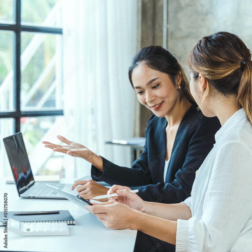 Two young Asian businesswoman discuss investment project working and planning strategy. Business people talking together with laptop computer at office. Two young Asian businesswoman discuss investment project working and planning strategy. Business people talking together with laptop computer at office.