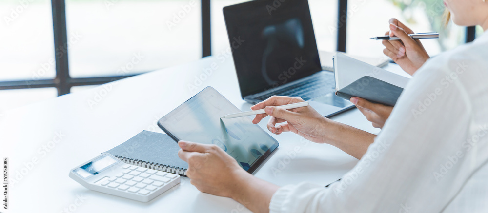 Two young Asian businesswoman discuss investment project working and planning strategy. Business people talking together with laptop computer at office. Two young Asian businesswoman discuss investment project working and planning strategy. Business people talking together with laptop computer at office.