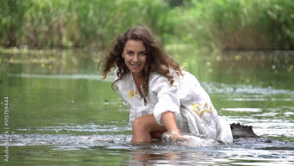 Girl sits on a curved tree trunk on the river bank and splashes water. Girl sits on a curved tree trunk on the river bank and splashes water.