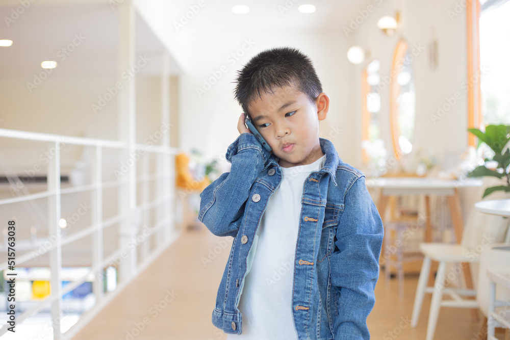 A five-year-old Asian boy stands by using a mobile phone. communicate with others Lifestyle concept in living in today's era A five-year-old Asian boy stands by using a mobile phone. communicate with others Lifestyle concept in living in today's era