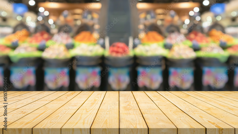 Empty wood table top with blur fruits in basket supermarket grocery store background