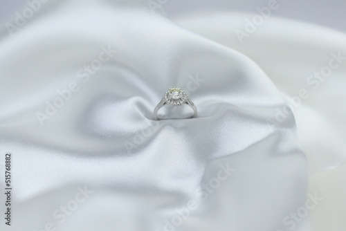 Fine jewelry as diamond ring with diamond with white satin fabric background. Jewelry shop concept