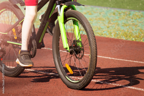 A boy on a bicycle rides around the stadium, the wheel is very close, cycling