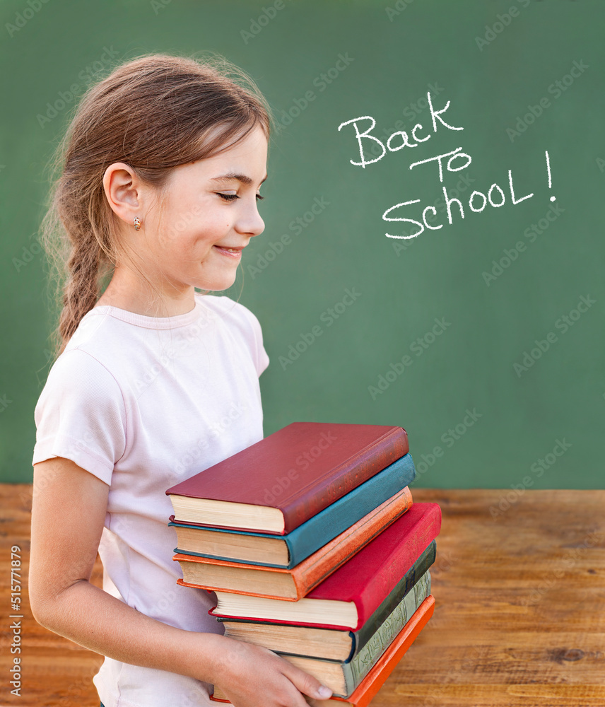a schoolgirl with a stack of books stands near the blackboard a schoolgirl with a stack of books stands near the blackboard
