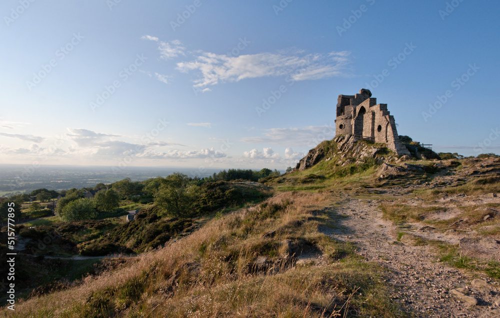 Mow Cop Castle, Cheshire / Staffordshire, England in sunlight with blue sky, clouds and distant landscape; landscape format.