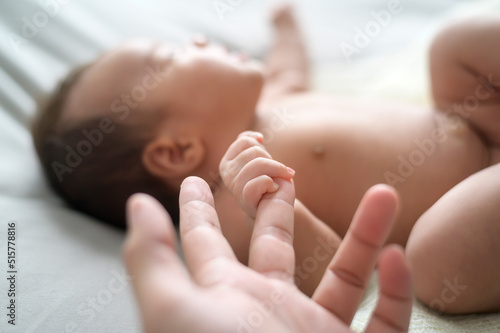 Close of hand holding new born baby's finger photo