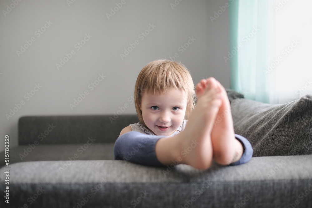 Cute girl child one gallops on couch in living room Cute girl child one gallops on couch in living room