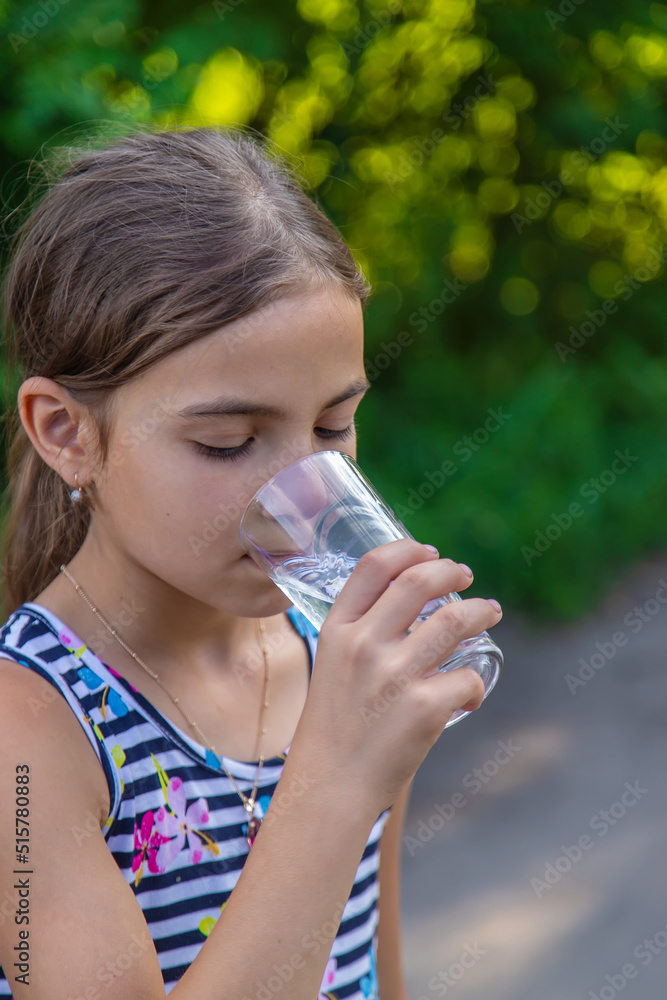 The child drinks water from a glass. Selective focus. The child drinks water from a glass. Selective focus.