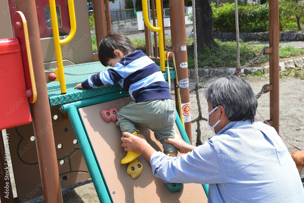 Fototapeta premium 公園の小さなボルダリングを登る幼児と祖父 2歳