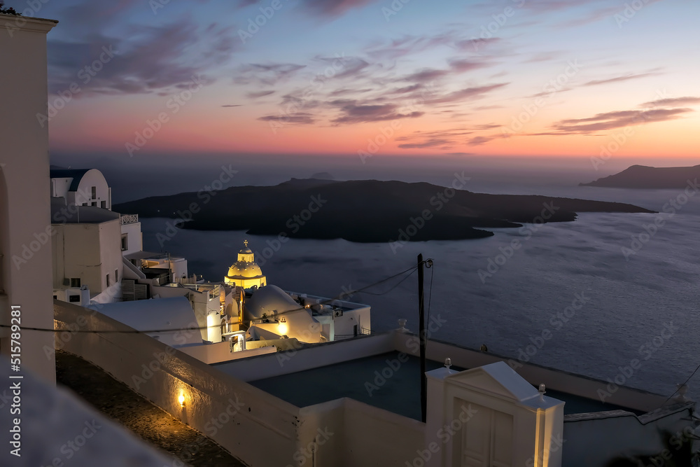 Panoramic view of the volcano, the illuminated  village of Fira and a stunning sunset of the Aegean Sea in Santorini