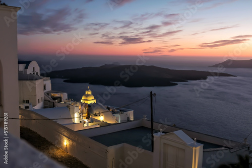 Panoramic view of the volcano, the illuminated village of Fira and a stunning sunset of the Aegean Sea in Santorini