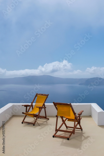 View of two empty sunbeds on the rooftop of a villa  and a spectacular view of the Aegean Sea  in Santorini Greece © DIMITRIOS