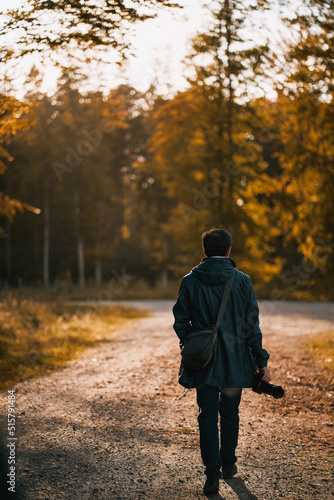 No face man back to the camera trekking in the autumn park with his camera. Photographer hobbyist outdoor