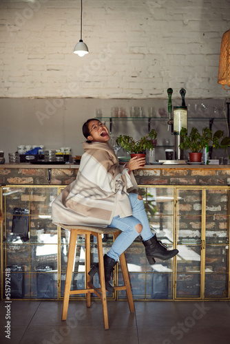 Portrait of laughing woman sits in a coffee shop and holding plant in her hands.