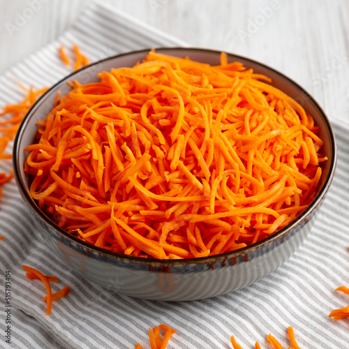 Raw Orange Carrot Shreds in a Bowl, side view.