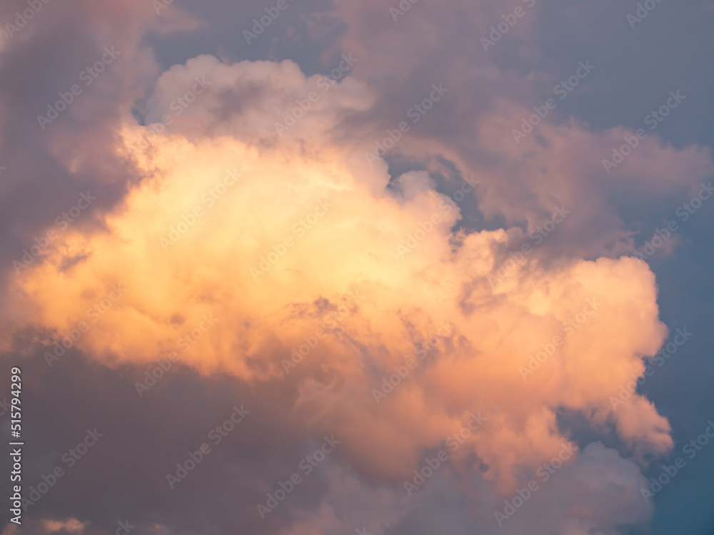 Cumulus clouds shines orange and pink at the horizon during the thunderstorm. Weather, clouds, temperature and meteorology.