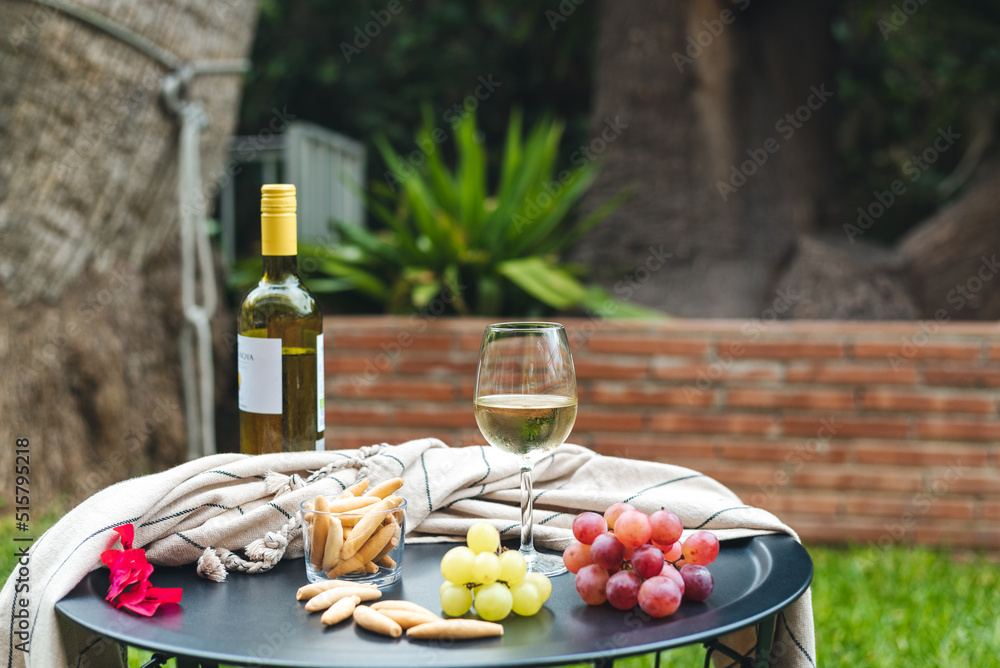 A glass of white wine with appetizers on the table.