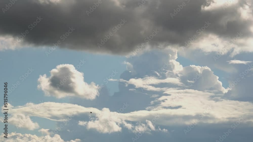 Light white clouds run across the blue sky. Above them are heavy dark clouds. Light white clouds run across the blue sky. Above them are heavy dark clouds.