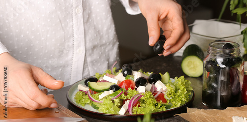 Woman preparing tasty Greek salad in kitchen, closeup