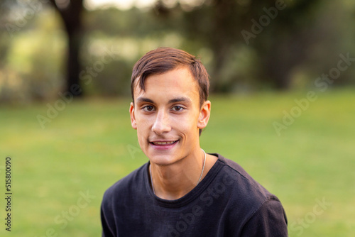 head and shoulders of teen boy outdoors looking at camera photo