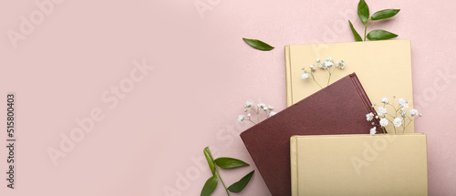 Books with floral decor on pink background with space for text photo