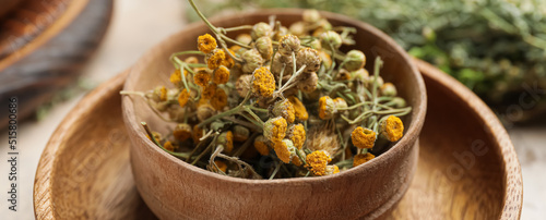 Wooden bowl with dried herbs on table, closeup