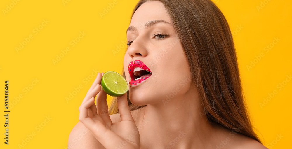 Beautiful young woman with creative makeup and lime on yellow background Beautiful young woman with creative makeup and lime on yellow background
