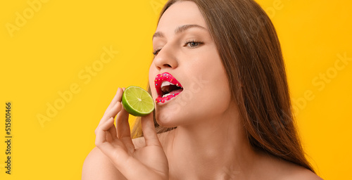 Beautiful young woman with creative makeup and lime on yellow background
