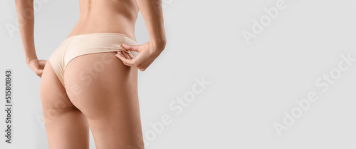 Slim young woman in underwear on light background with space for text