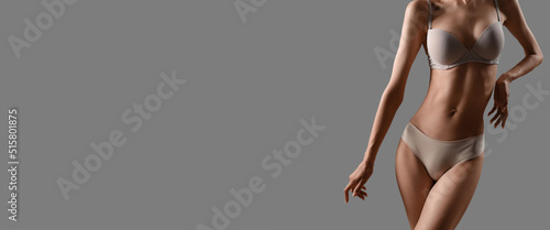 Slim young woman in underwear on grey background with space for text