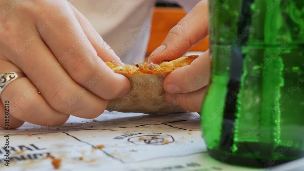 a woman eats a turkish pide with the fingers of her hand tears a slice of peda with cheese on a plate close-up. Lunch at a street Turkish restaurant in the open air. a woman eats a turkish pide with the fingers of her hand tears a slice of peda with cheese on a plate close-up. Lunch at a street Turkish restaurant in the open air.
