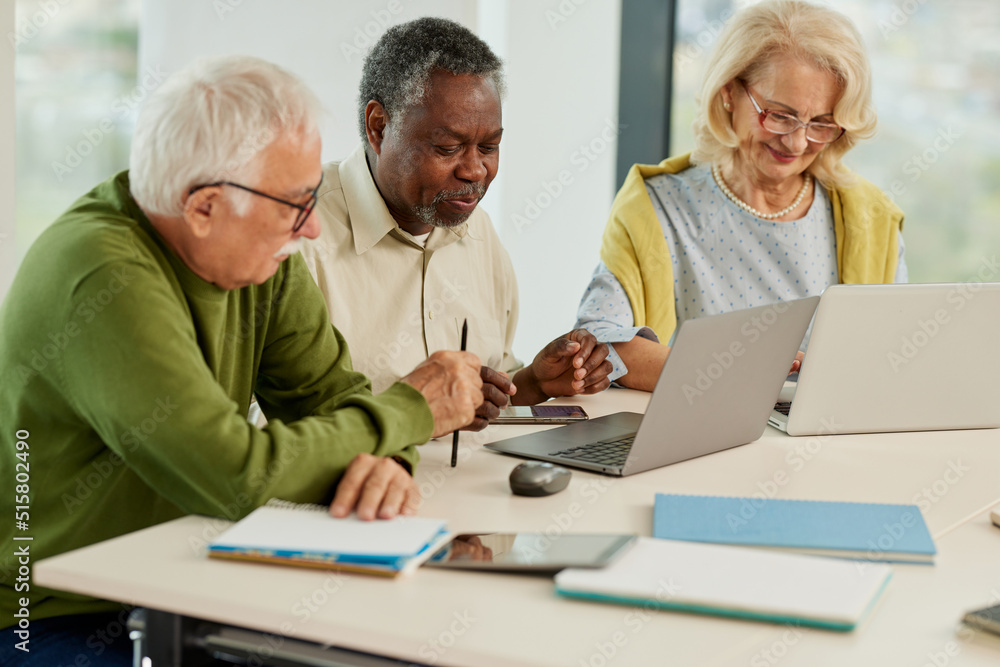 A cheerful multicultural group of senior students is doing an assignment on laptops in the classroom. A cheerful multicultural group of senior students is doing an assignment on laptops in the classroom.