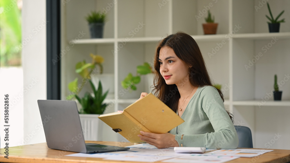 Attractive female freelancer working online with laptop computer in her home office Attractive female freelancer working online with laptop computer in her home office