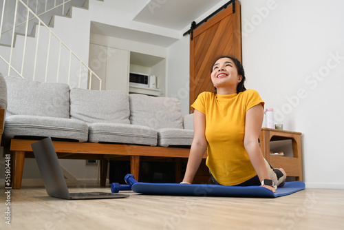 Pretty young woman doing exercise and stretching body on mat at home. Healthy lifestyle concept