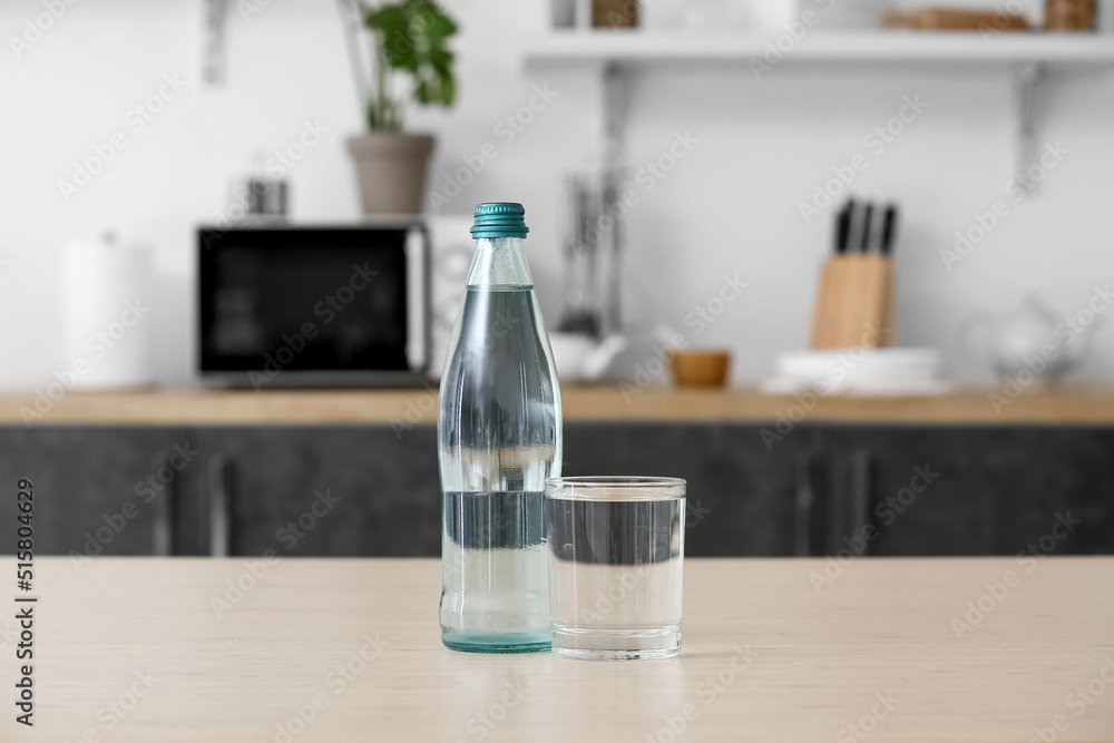 Bottle and glass of clean water on kitchen table Bottle and glass of clean water on kitchen table