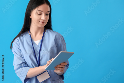 Female medical assistant using tablet computer on blue background