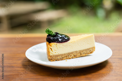 Piece of cheesecaket and blueberry sauce on white plate