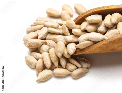 Closeup view of wooden scoop with peeled sunflower seeds on white background photo