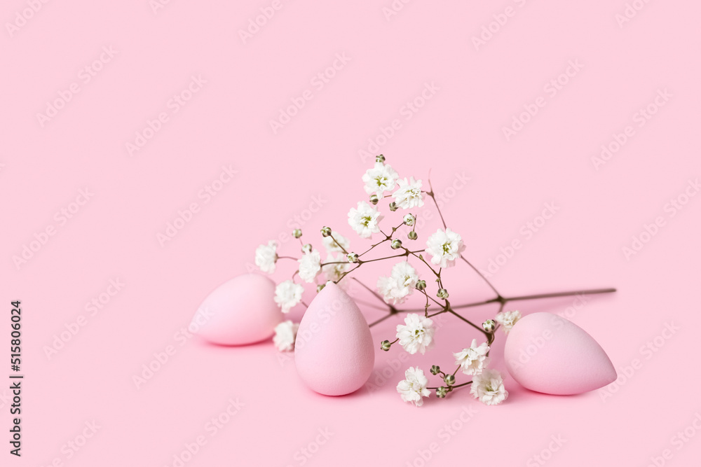 Makeup sponges and gypsophila flowers on pink background