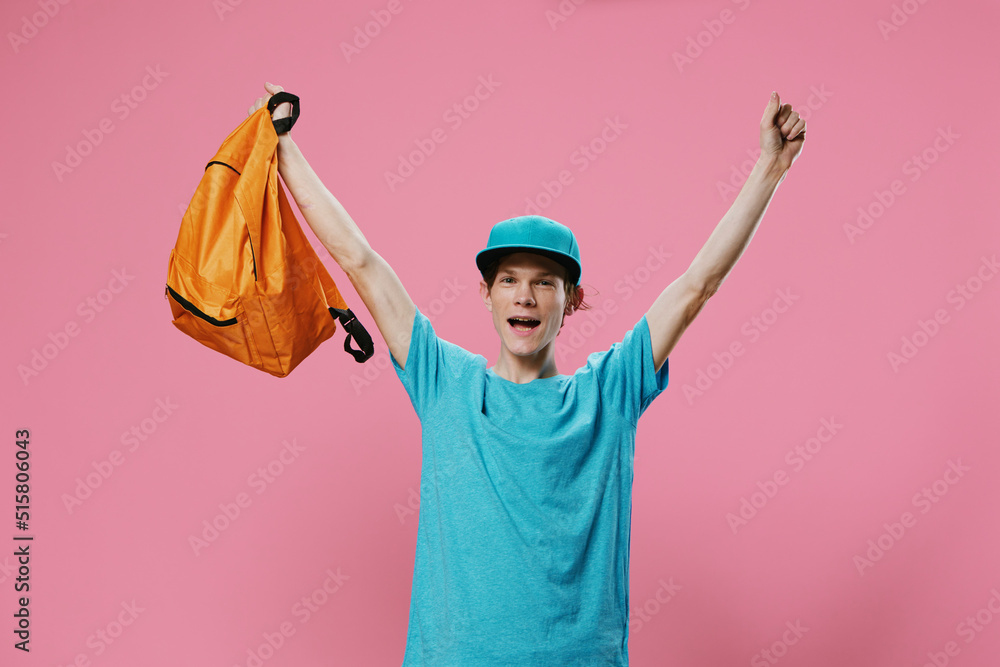 happy, joyful guy enthusiastically raises his hands up holding a bright backpack. happy, joyful guy enthusiastically raises his hands up holding a bright backpack.